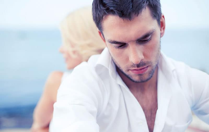 sad man wearing sitting at the back of a blonde haired woman