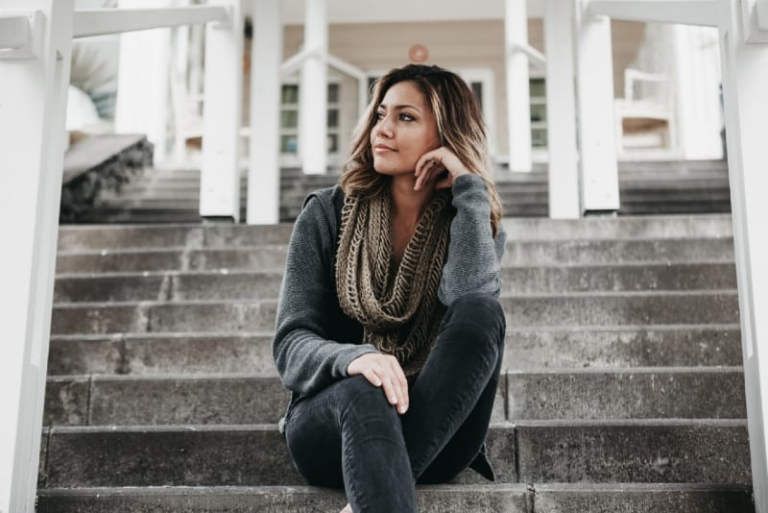 woman in gray scarf sitting on stairs