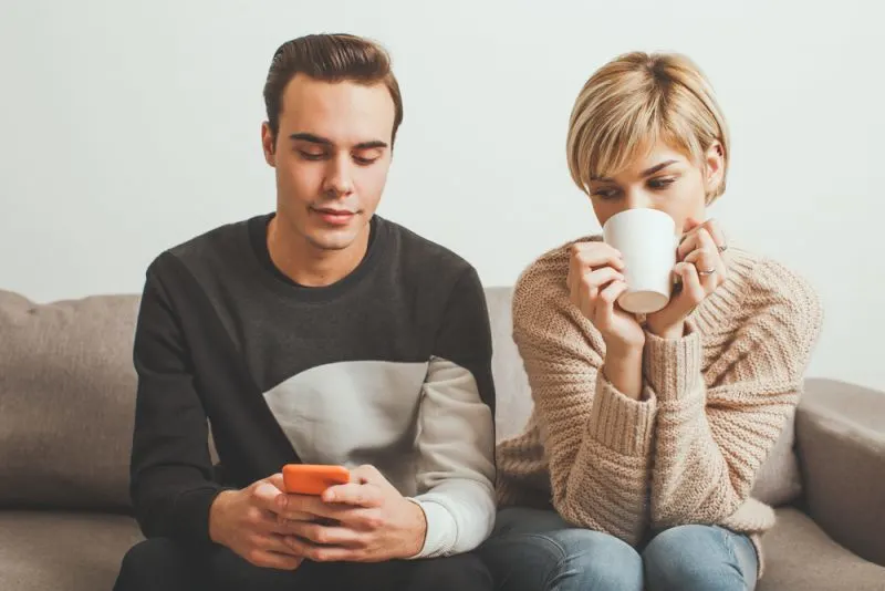 Jealous girl spying her boyfriend's mobile phone
