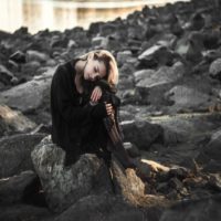 woman in black dress sitting on rock