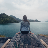 woman sitting on wooden dock looking at water