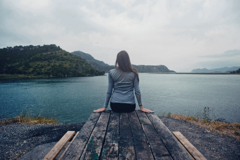 woman sitting on wooden dock looking at water