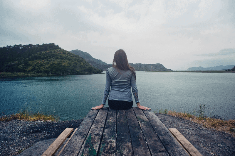 woman sitting on wooden dock looking at water