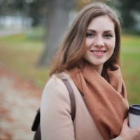 mujer sosteniendo una taza mientras sonríe al aire libre