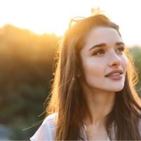 mulher bonita a sorrir olhando para longe, de pé ao ar livre