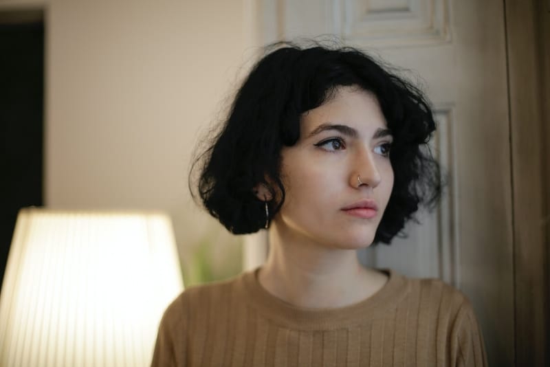 woman in brown shirt standing near door