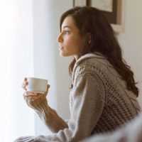 thinking woman sitting and holding a cup of coffee