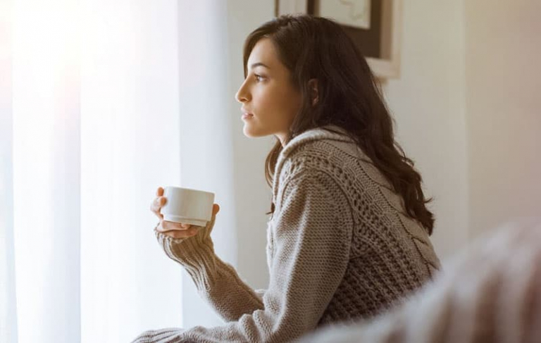 thinking woman sitting and holding a cup of coffee