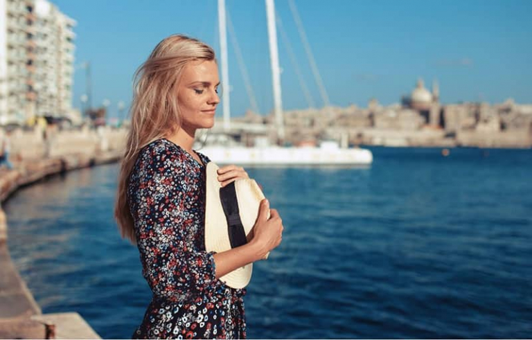 young woman with closed eyes standing near the sea