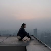 mujer sentada en un tejado mirando los edificios