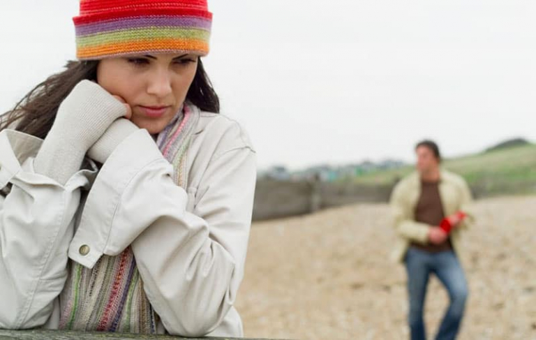 pensive woman with a bonnet leaning with a man in blurred background