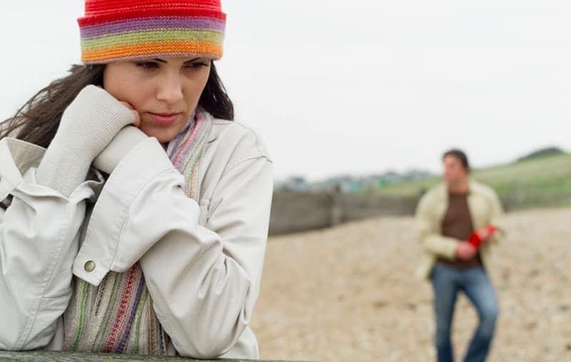 pensive woman with a bonnet leaning with a man in blurred background
