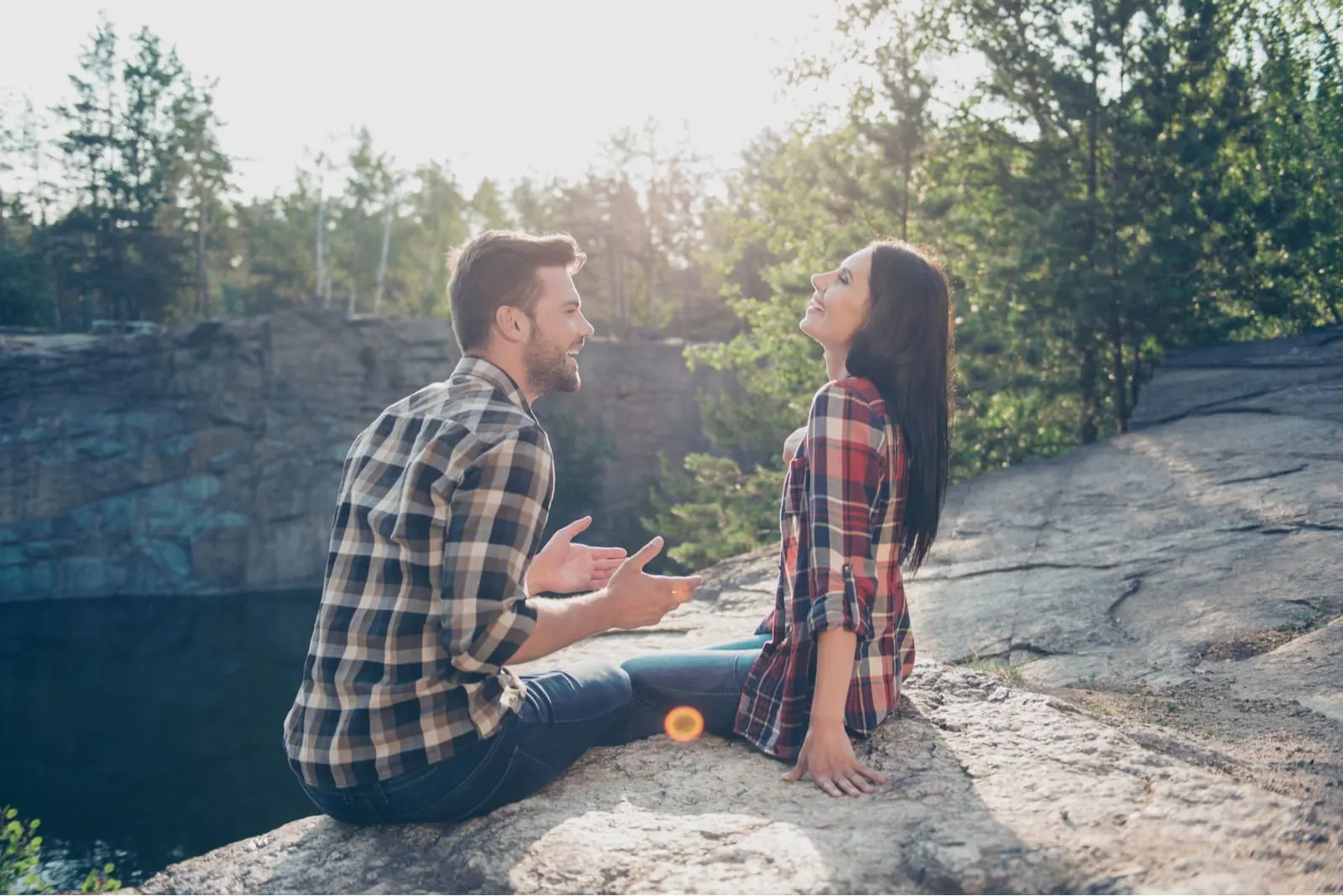 a smiling couple having fun on a rock in nature