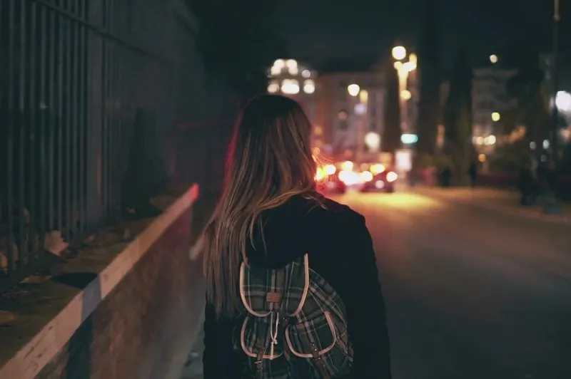 a woman with a backpack walks down the street