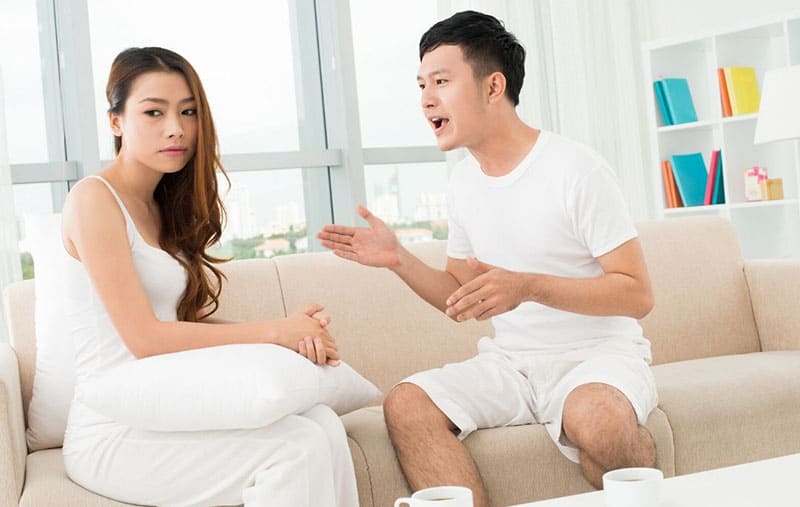 Asian couple arguing sitting in the sofa inside living room
