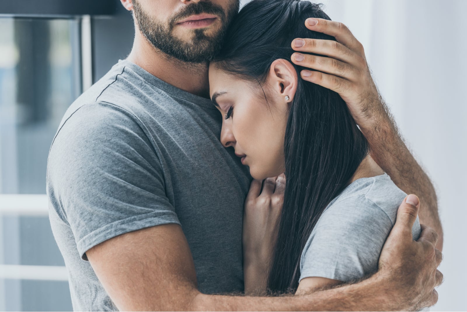 bearded man hugging and supporting young sad woman