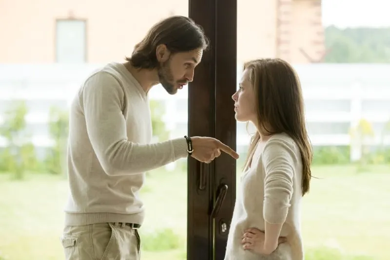 man and woman arguing while standing near door