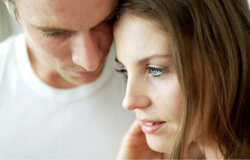 couple close together with man's face touching woman's head in focus photography