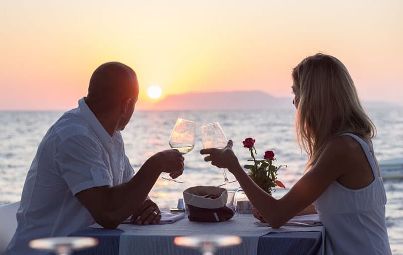 casal a namorar com um copo de vinho a olhar para o pôr do sol