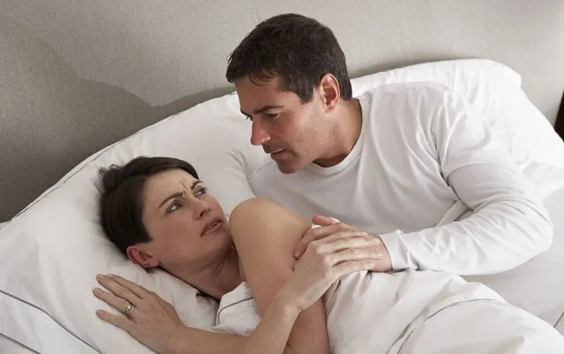 couple having disagreement in bed man trying to touch her
