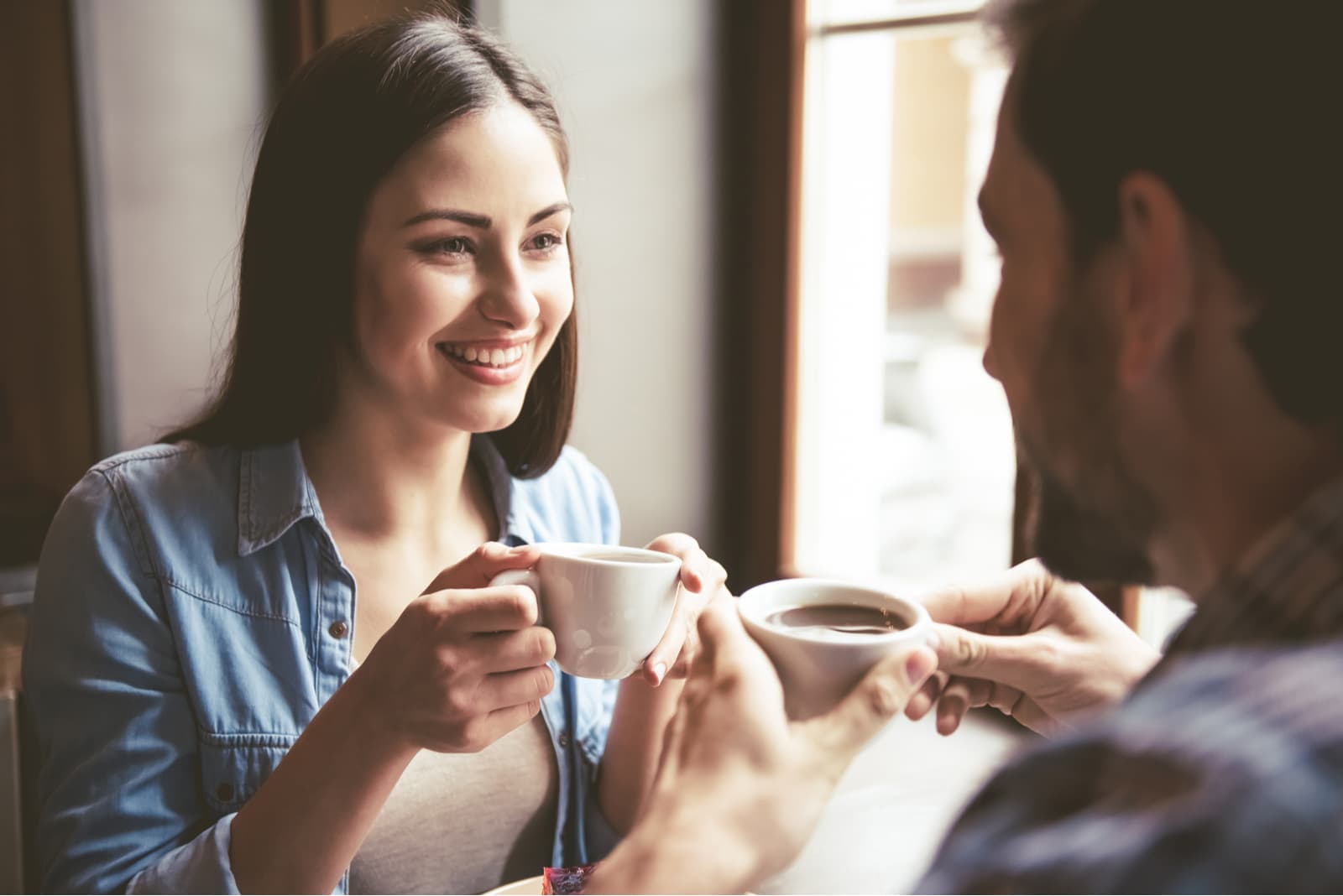 casal a segurar chávenas de café e a conversar