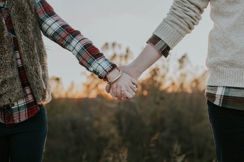 hombre y mujer cogidos de la mano al aire libre