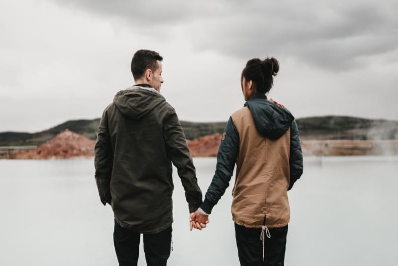 hombre y mujer cogidos de la mano cerca del agua