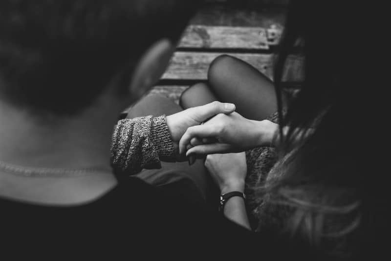 hombre y mujer cogidos de la mano sentados al aire libre