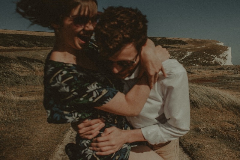 woman in floral dress and man hugging outdoor