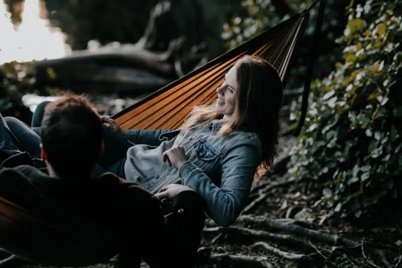 man and woman lying on hammock and talking