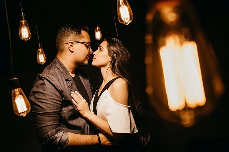 couple on nose to nose with light bulbs surrounding them
