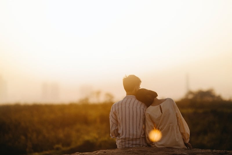 man in striped shirt and woman sitting near grass field