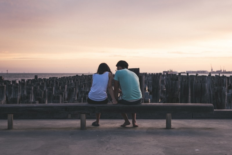 man and woman sitting on bench and talking