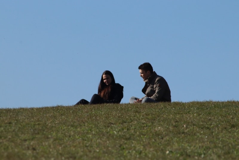 man and woman sitting on grass and talking