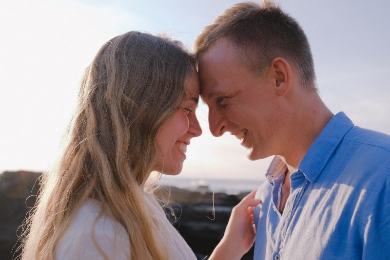 uomo sorridente in camicia blu e donna in piedi all'aperto