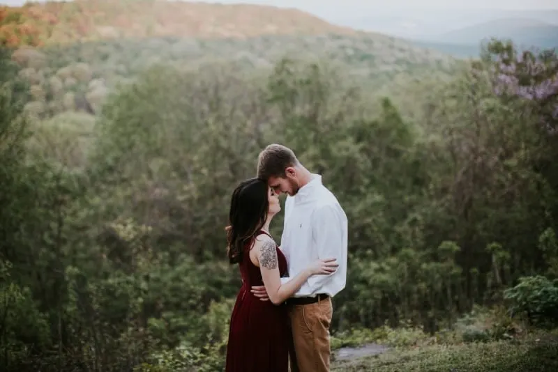 man and woman standing in forest and hugging
