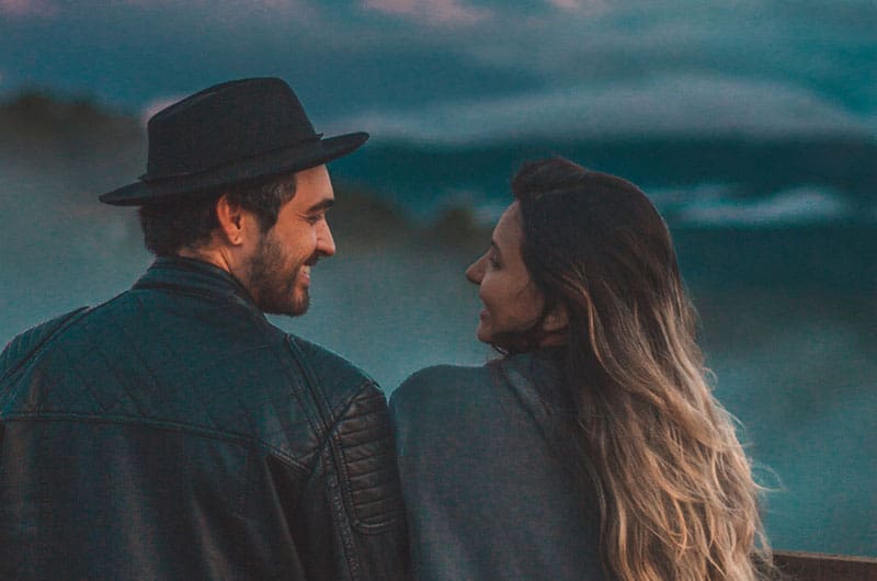 casal a olhar um para o outro na hora dourada, de frente para as nuvens