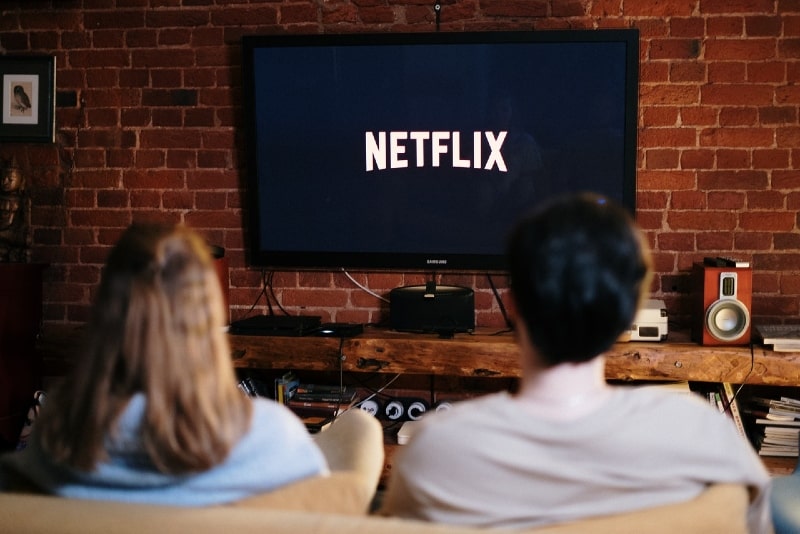 man and woman watching tv while sitting on sofa