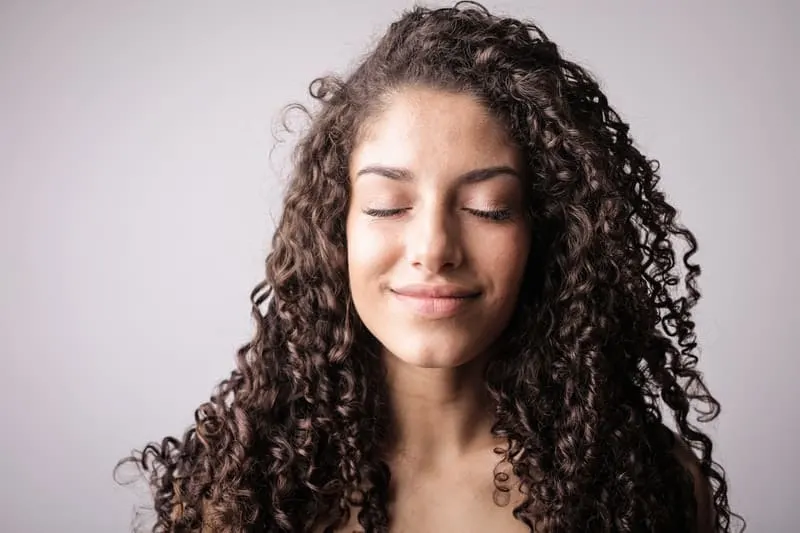 curly haired woman closing her eyes and smiling