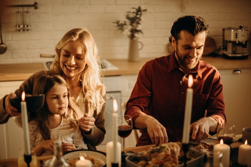 father mother and daughter having dinner at table