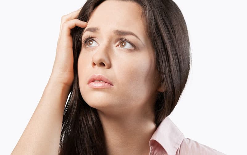 focused face of a woman confused with hand on her head