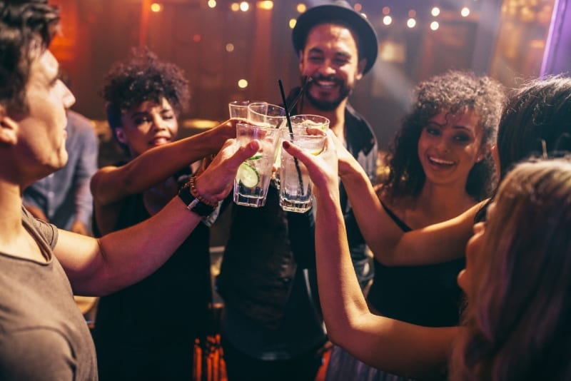 Gruppo di amici che brinda con un cocktail al bar