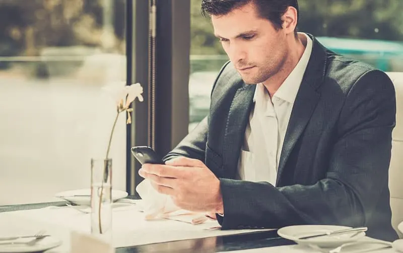 handsome man using a smartphone inside the restaurant