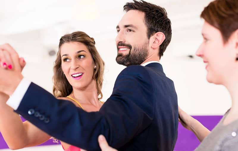 instructor in dance school teaching a couple to dance