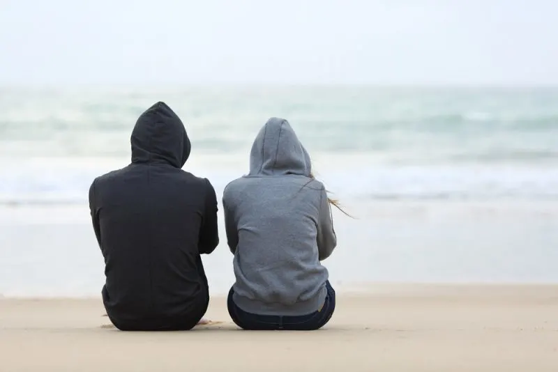 man and woman sitting on the beach talking