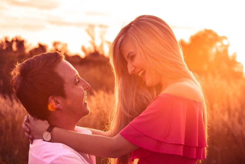 hombre sonriente con mujer en top rosa