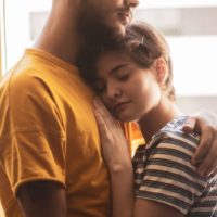 man in yellow t-shirt hugging woman