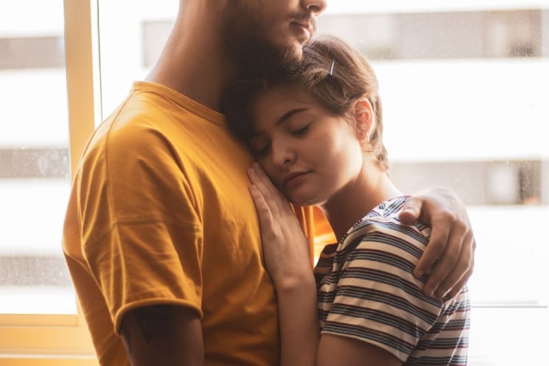 man in yellow t-shirt hugging woman