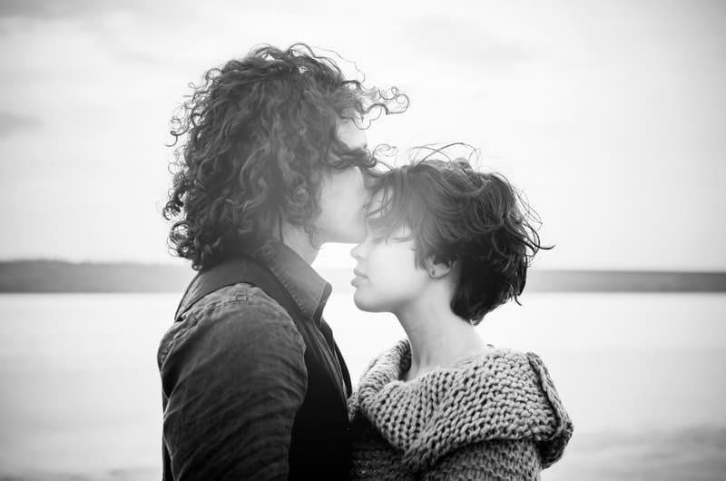 man kissing forehead of a woman in grayscale photography