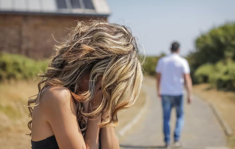 man leaving a woman crying in the street near the house